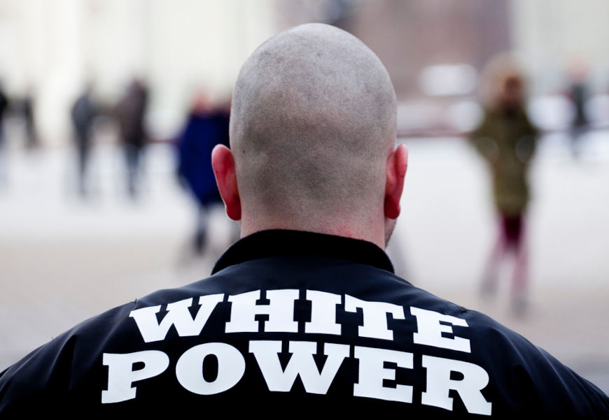 Supremacista visto de costas. Em sua roupa hÃ¡ a expressÃ£o â€œwhite powerâ€, poder branco.