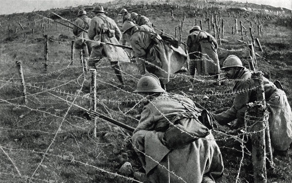 Soldados franceses rastejando por baixo de arames farpados na Batalha de Verdun, durante a Primeira Guerra