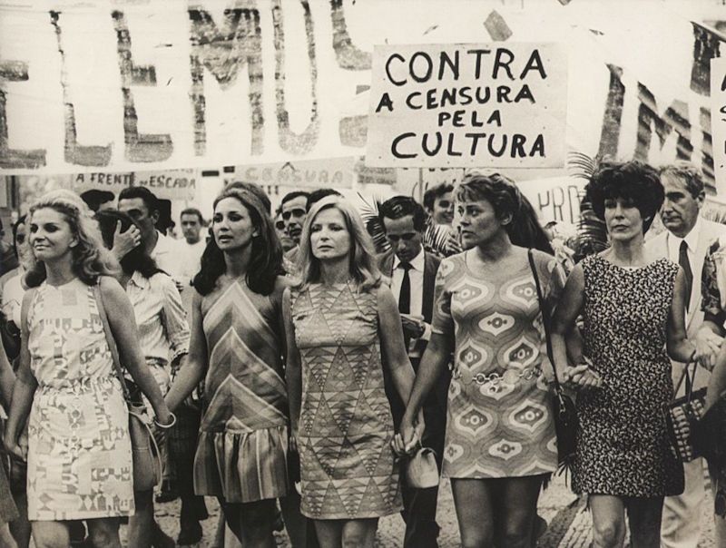 Mulheres artistas de mÃ£os dadas em protesto, em 1968, em texto sobre o tropicalismo.