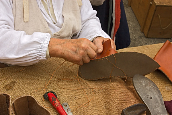 Homem costurando sapato em texto sobre manufatura.