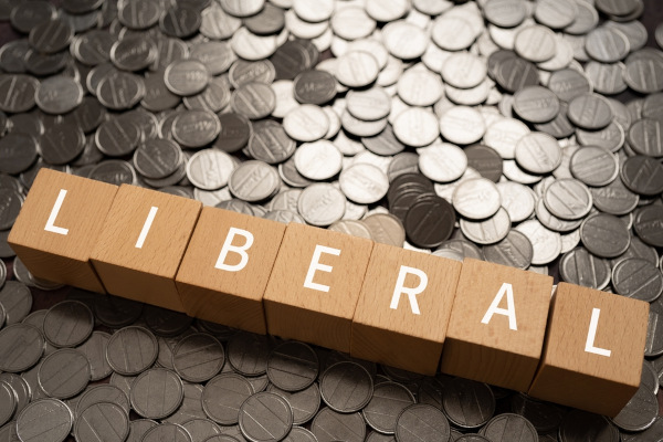 Palavra “liberal” em blocos de madeira sobre moedas, em texto sobre liberalismo econômico.