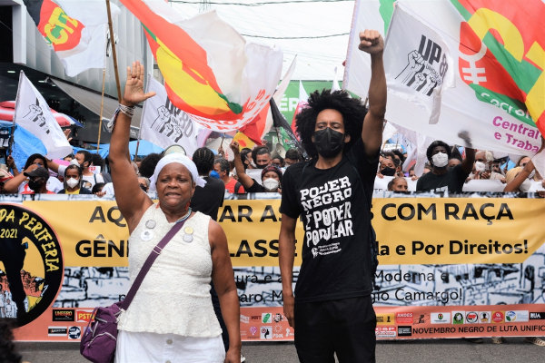 Homem e mulher liderando multidão em uma manifestação do movimento negro.