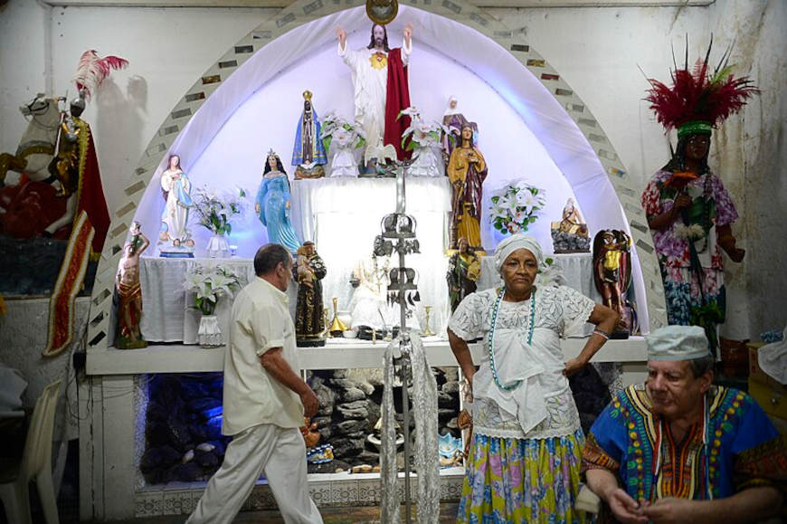 Praticantes da umbanda prÃ³ximos a um congÃ¡, altar no qual estÃ£o representados os orixÃ¡s e as entidades espirituais.